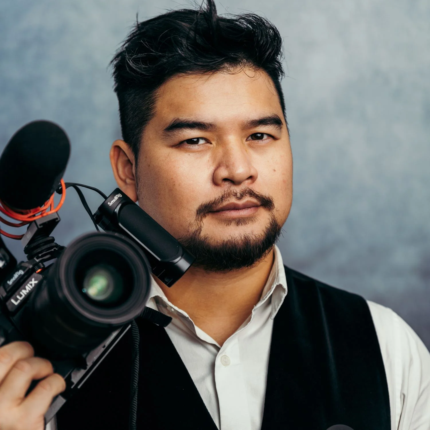 Visage de la Créativité : Yo DAO de Yo Production Portrait de Yo DAO, vidéaste de mariage professionnel, tenant une caméra vidéo LUMIX GH6 équipée d'un microphone, prêt à filmer